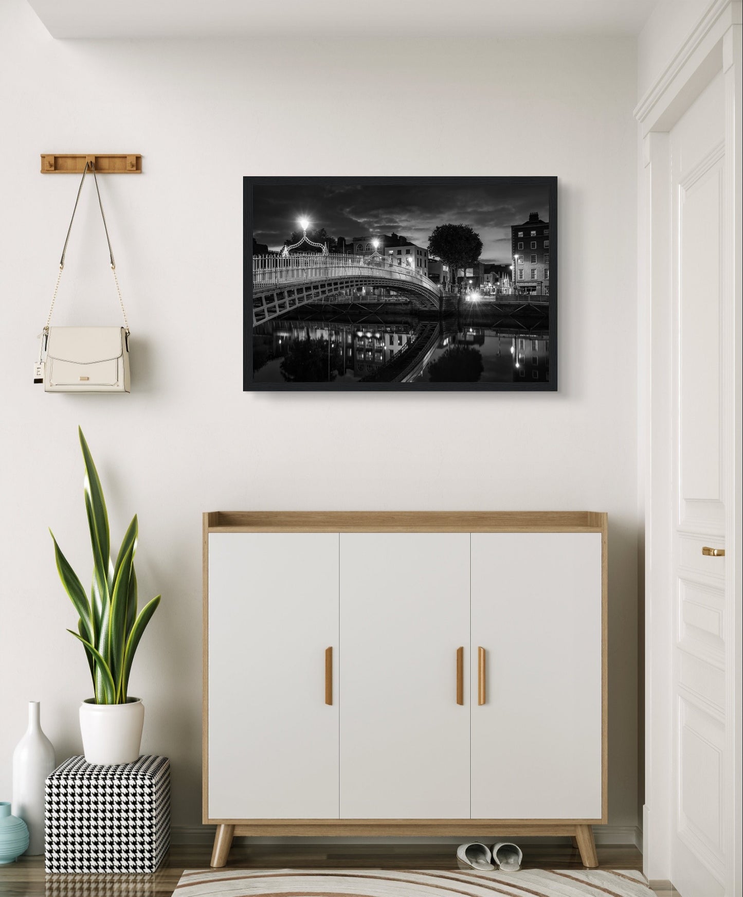 Black and white framed wall art print of the Ha'penny Bridge in Dublin at night. The bridge's historic architecture is beautifully highlighted against the dark sky, with reflections shimmering in the River Liffey below. Ideal for adding elegance to any room or office.