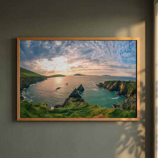 Dingle Peninsula framed print in a natural oak frame on a dark green wall beside a window, dappled plant shadow