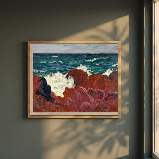 Red Rocks and Sea framed print in a natural oak frame on a dark green wall beside a window, dappled plant shadow