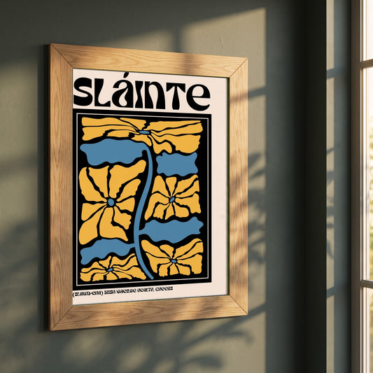 Sláinte framed print in a natural oak frame on a dark green wall beside a window, dappled plant shadow