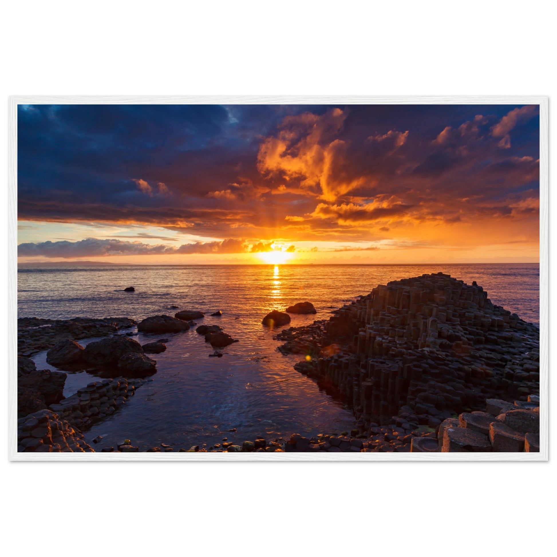 Framed art print of a mesmerizing sunset at Giant's Causeway, showcasing iconic basalt columns against a sky painted with warm hues. The scene captures nature's beauty and tranquility, adding a sophisticated touch to home or office decor. Perfect for any art lover.