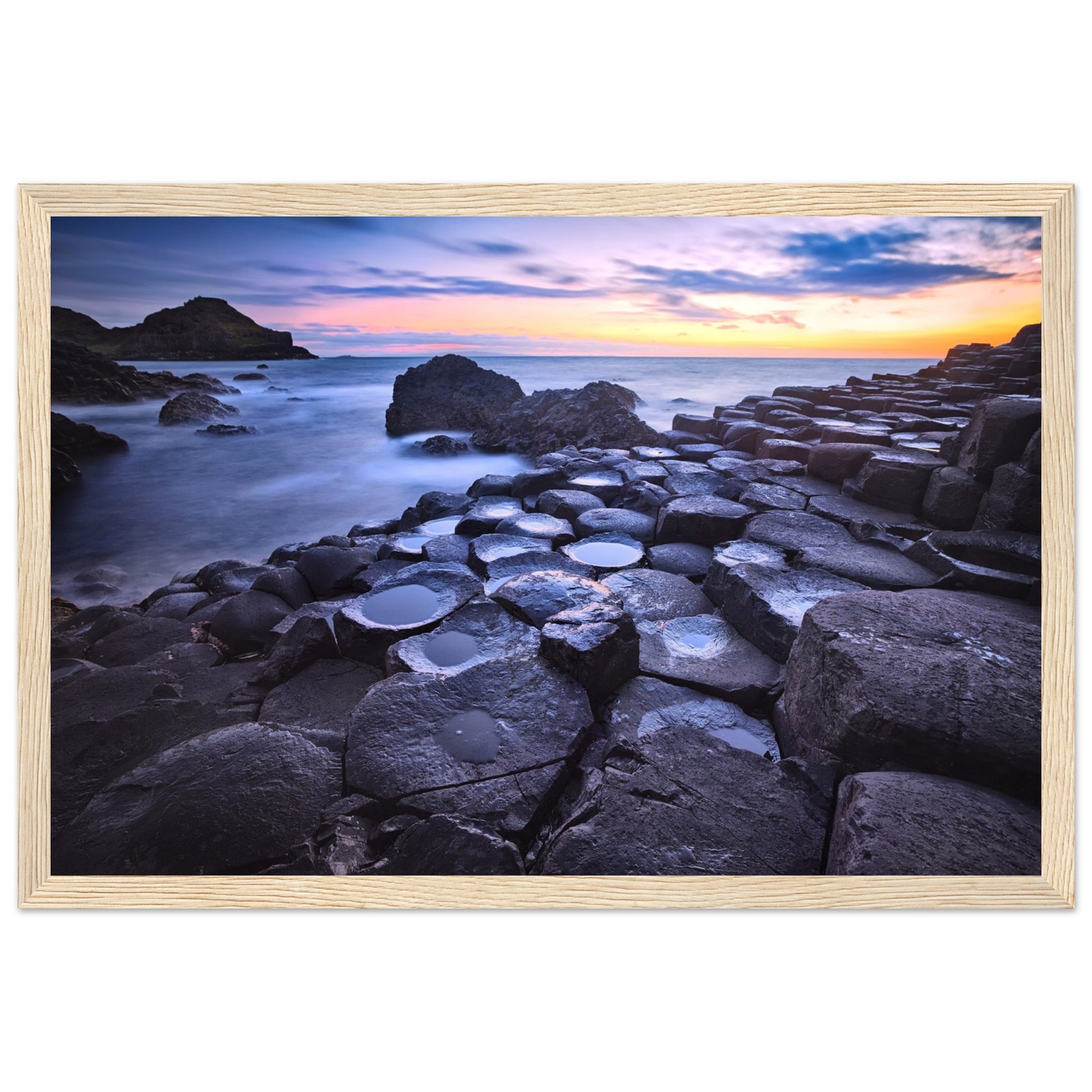 Framed art print of a breathtaking sunset at Giant's Causeway. Features iconic basalt columns against a warm, colorful sky. Perfect for adding sophistication and natural beauty to any home or office decor. Ideal for nature and art enthusiasts.