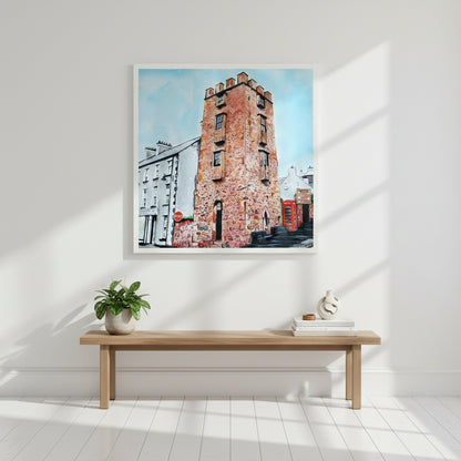 50×50 cm white-framed art print of The Curfew Tower Cushendall positioned above a hallway bench, bright modern home, sunlit interior, high-key aesthetic, premium editorial-style product mock-up.