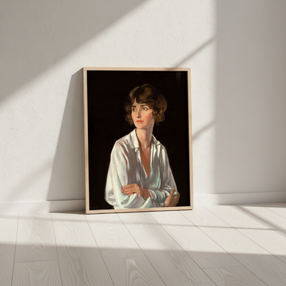 A framed portrait print leaning against a white wall on a light wood floor, showing a woman in a white blouse against a dark background. The room has soft window-box shadows cast across the wall and floor.
