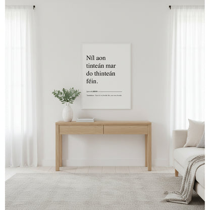 Níl aon tinteán mar do thinteán féin. Translation: There Is No Fireside Like Your Own Fireside. This Irish language framed print makes a great present, birthday gift and ideal Irish housewarming gift, or for Gaelic speakers. Irish proverb print ‘Níl aon tinteán mar do thinteán féin’ in a white gallery frame, bright Scandi living room, white walls, pale oak console, ceramic vase with eucalyptus, diffused daylight, clean magazine aesthetic.”