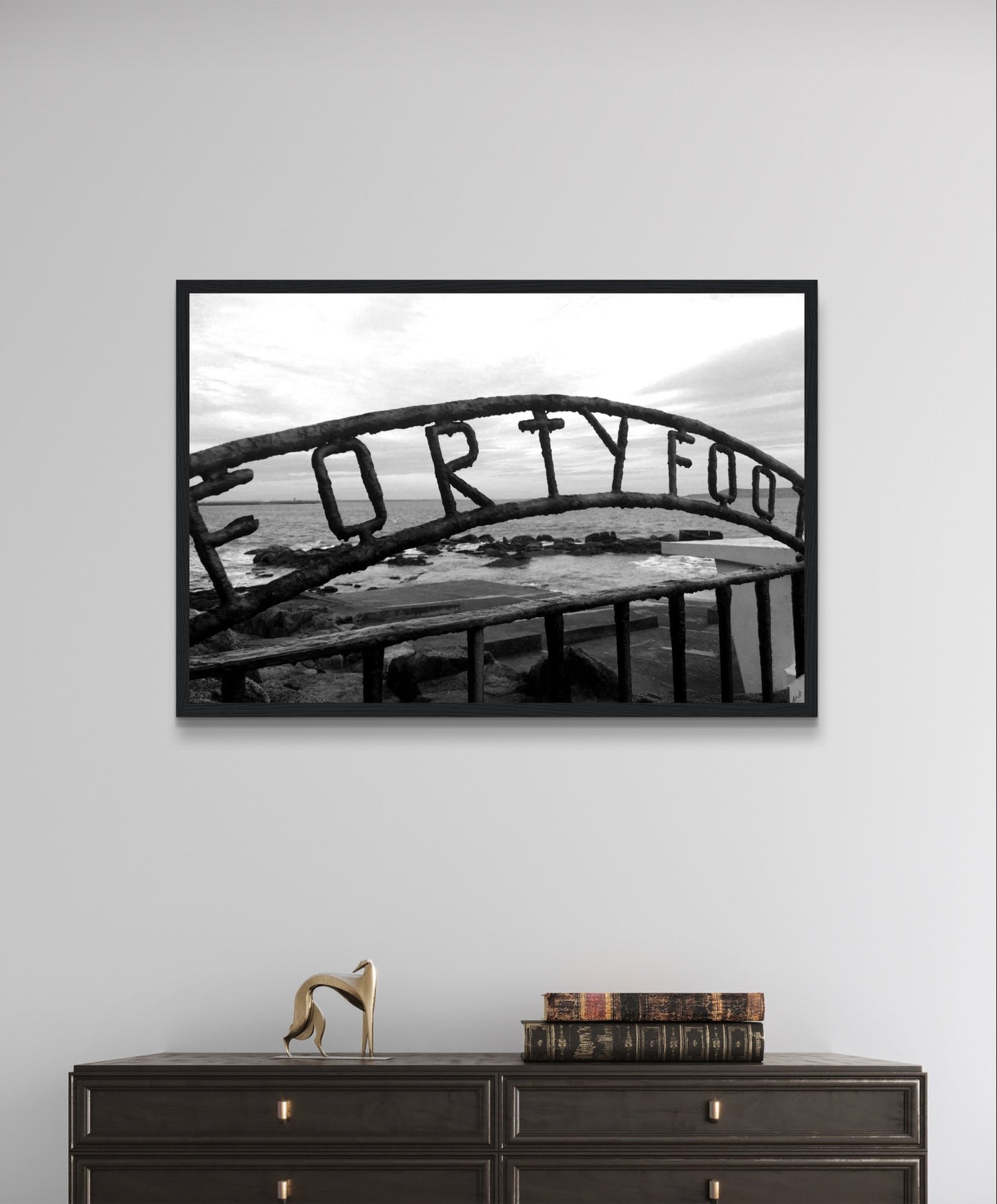 Monochrome seascape photo capturing the serene beauty of the Forty Foot bathing spot in Dublin, Ireland. Martello tower stands in the distance against a clear sky.