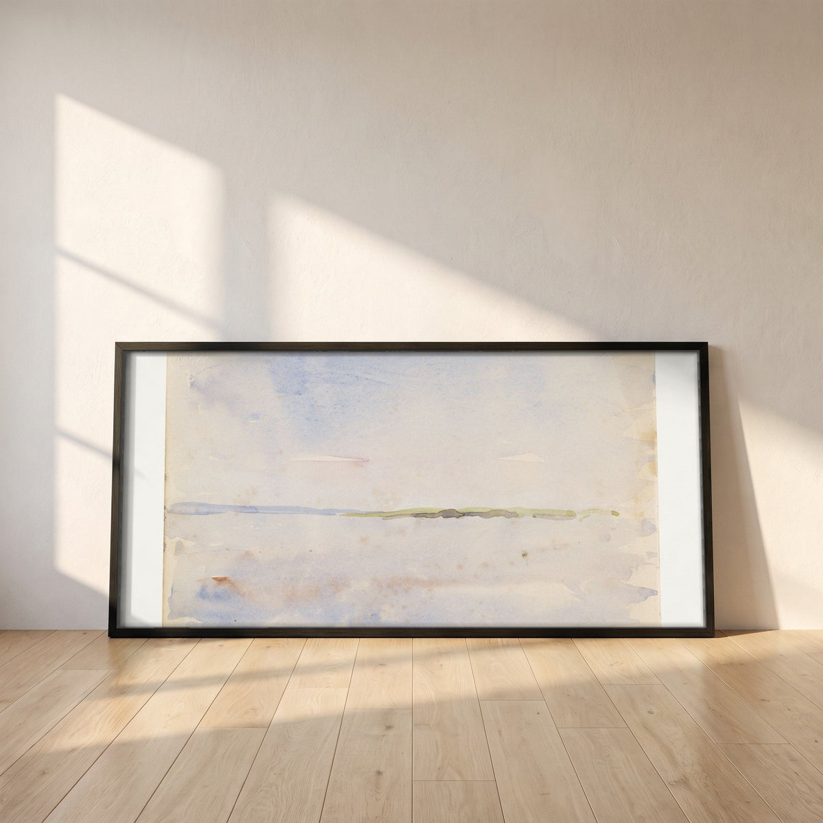 A Distant Coastline framed print in a black frame leaning against a white plaster wall on oak floorboards in morning light