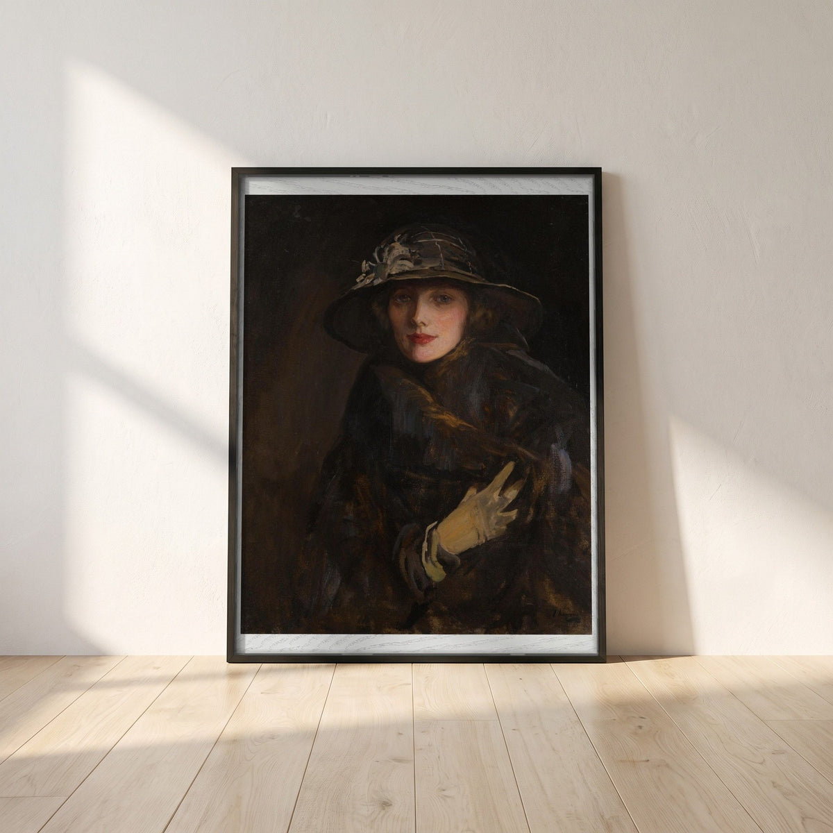 A Lady in Brown (1920) framed print in a black frame leaning against a white plaster wall on oak floorboards in morning light