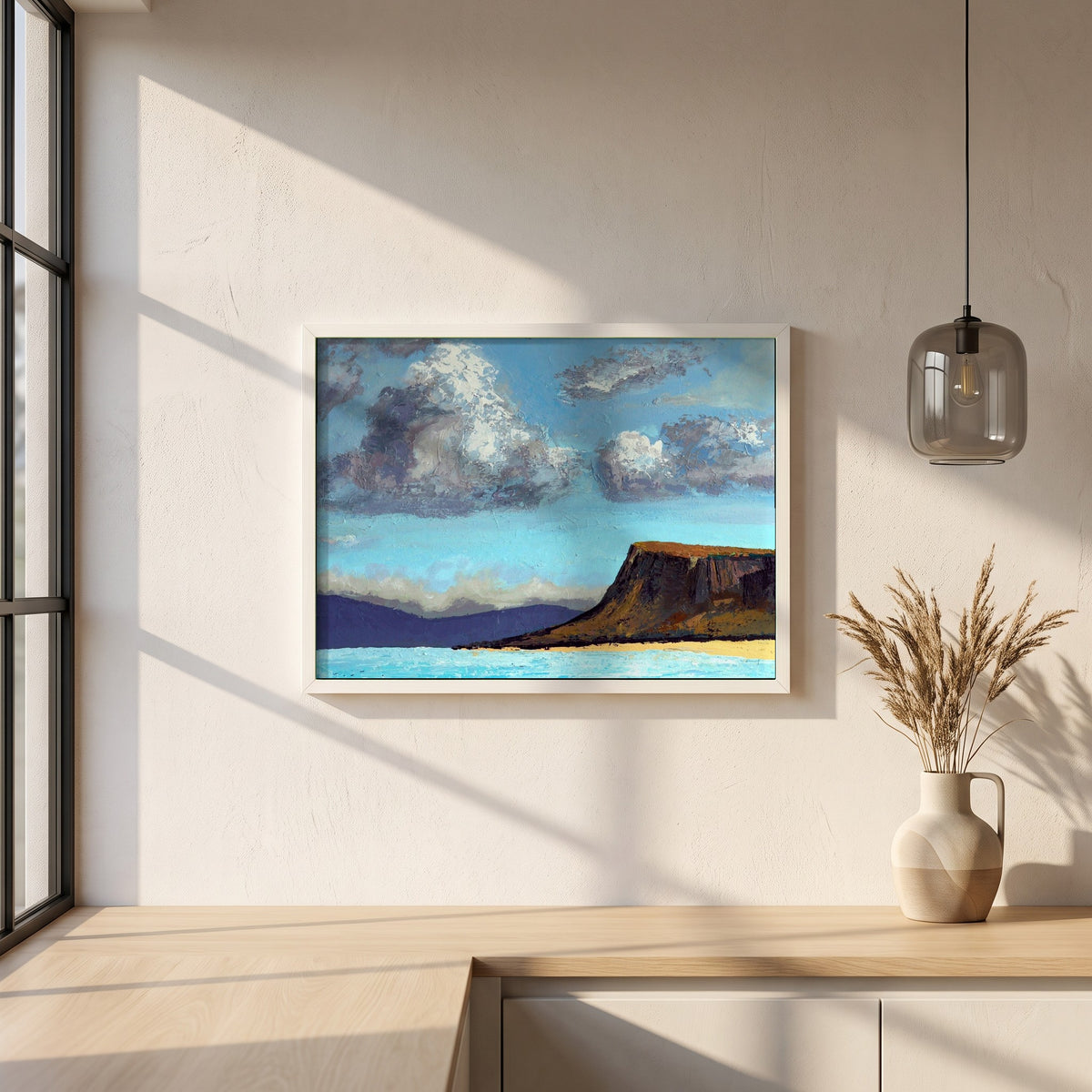 Fair Head from the Sea framed print in a white frame on a plaster wall above an oak worktop in a bright Scandinavian kitchen