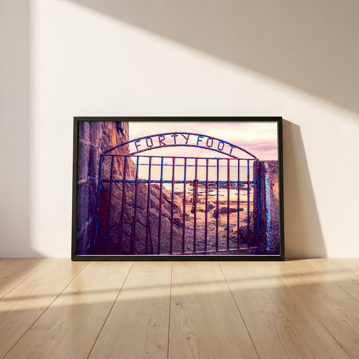 Forty Foot Gate Swimming Sandycove framed print in a black frame leaning against a white plaster wall on oak floorboards in morning light