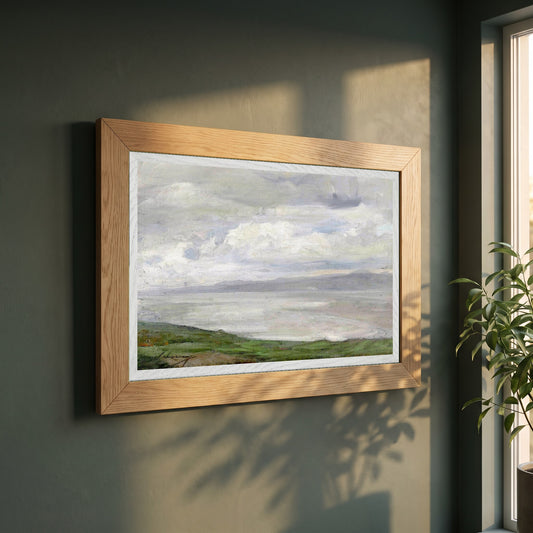 Island Magee framed print in a natural oak frame on a dark green wall beside a window, dappled plant shadow