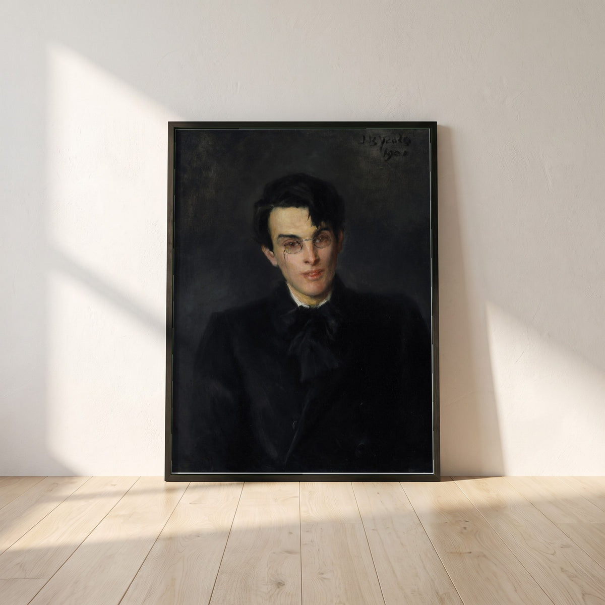 Portrait of W.B. Yeats framed print in a black frame leaning against a white plaster wall on oak floorboards in morning light