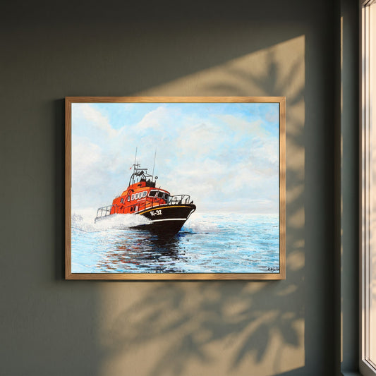RNLI Lifeboat framed print in a natural oak frame on a dark green wall beside a window, dappled plant shadow