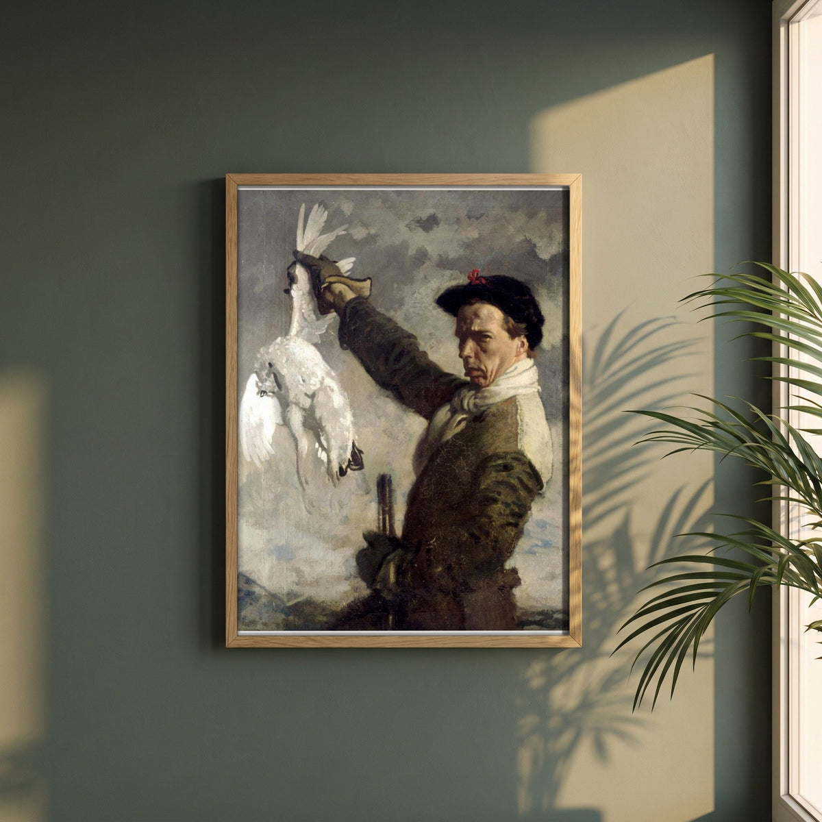 The Dead Ptarmigan (Self-Portrait) by William Orpen framed print in a natural oak frame on a dark green wall beside a window, dappled plant shadow