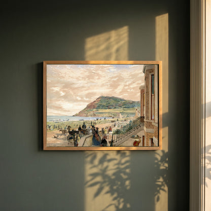 The Seafront at Bray framed print in a natural oak frame on a dark green wall beside a window, dappled plant shadow