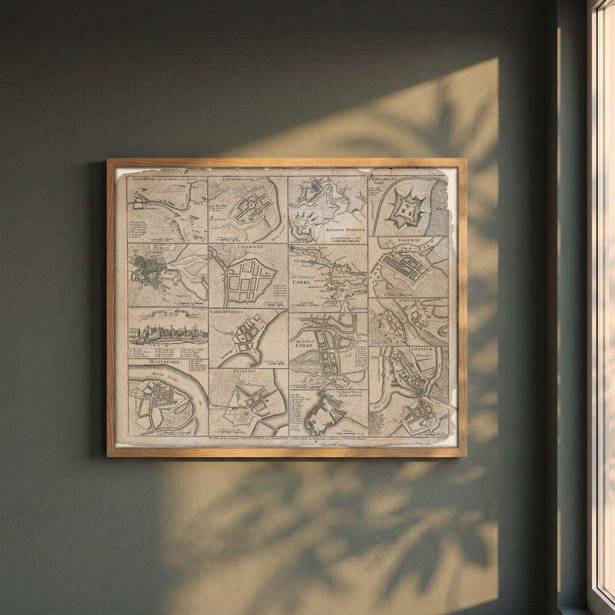 Plans of the Towns, Forts and Harbours of Ireland 1748 Map Print framed print in a natural oak frame on a dark green wall beside a window, dappled plant shadow